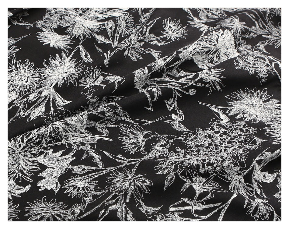 Close-up of white botanical linework printed across black shirt fabric.