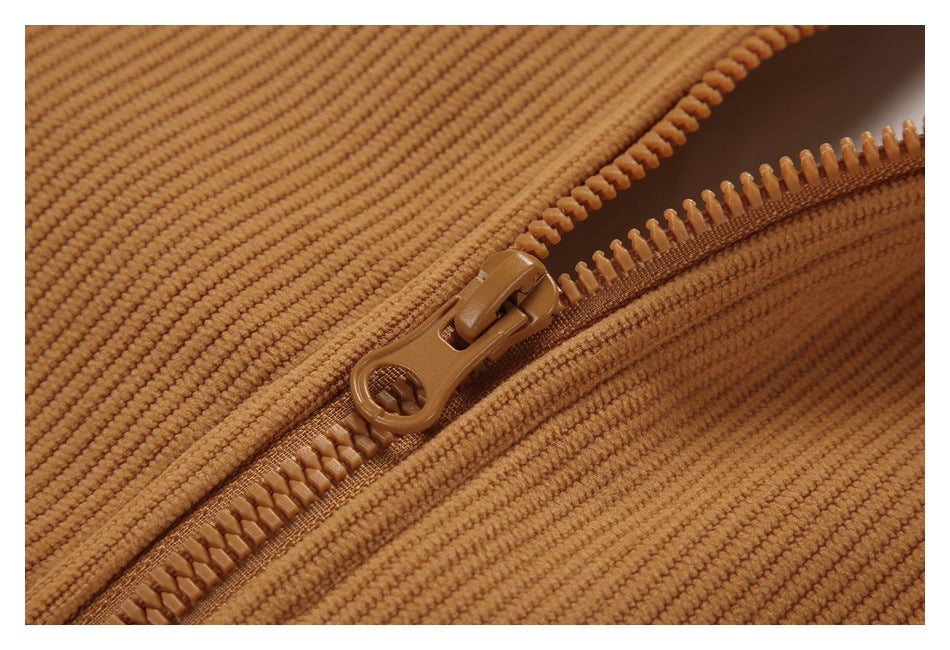 Close-up of a brown zipper and pull on tan ribbed fabric.