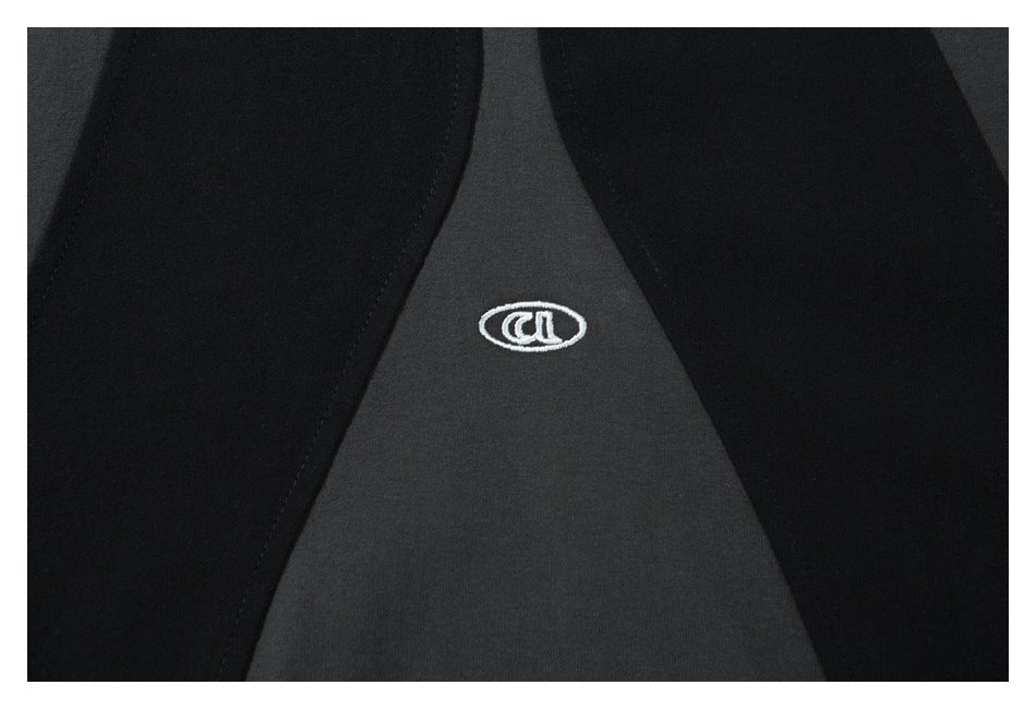 Close-up of a small white embroidered emblem on a charcoal shirt panel between black panels.