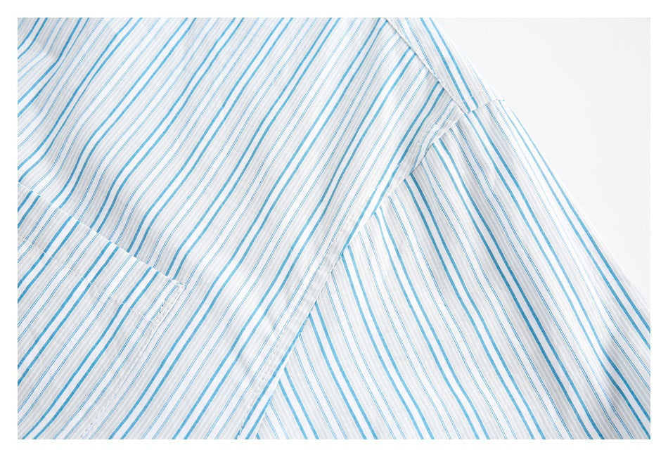Close-up of overlapping panels on a white shirt with thin blue and gray stripes and visible stitching.