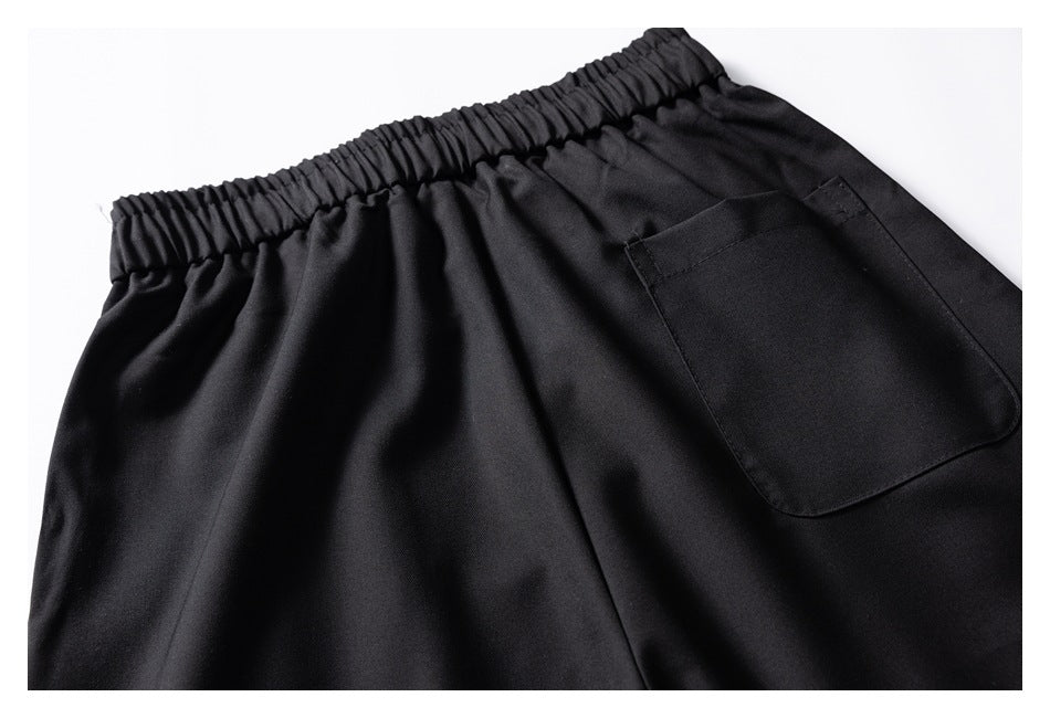 Close-up of black pants showing an elastic waistband and a rectangular back pocket.