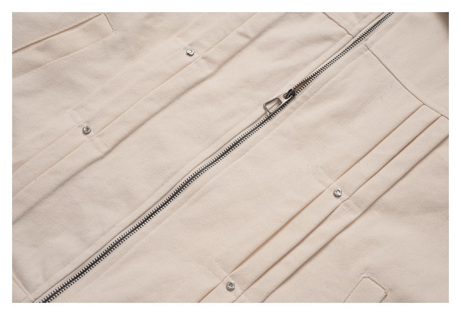 Close-up of a beige jacket's metal zipper and snap-fastened front placket.