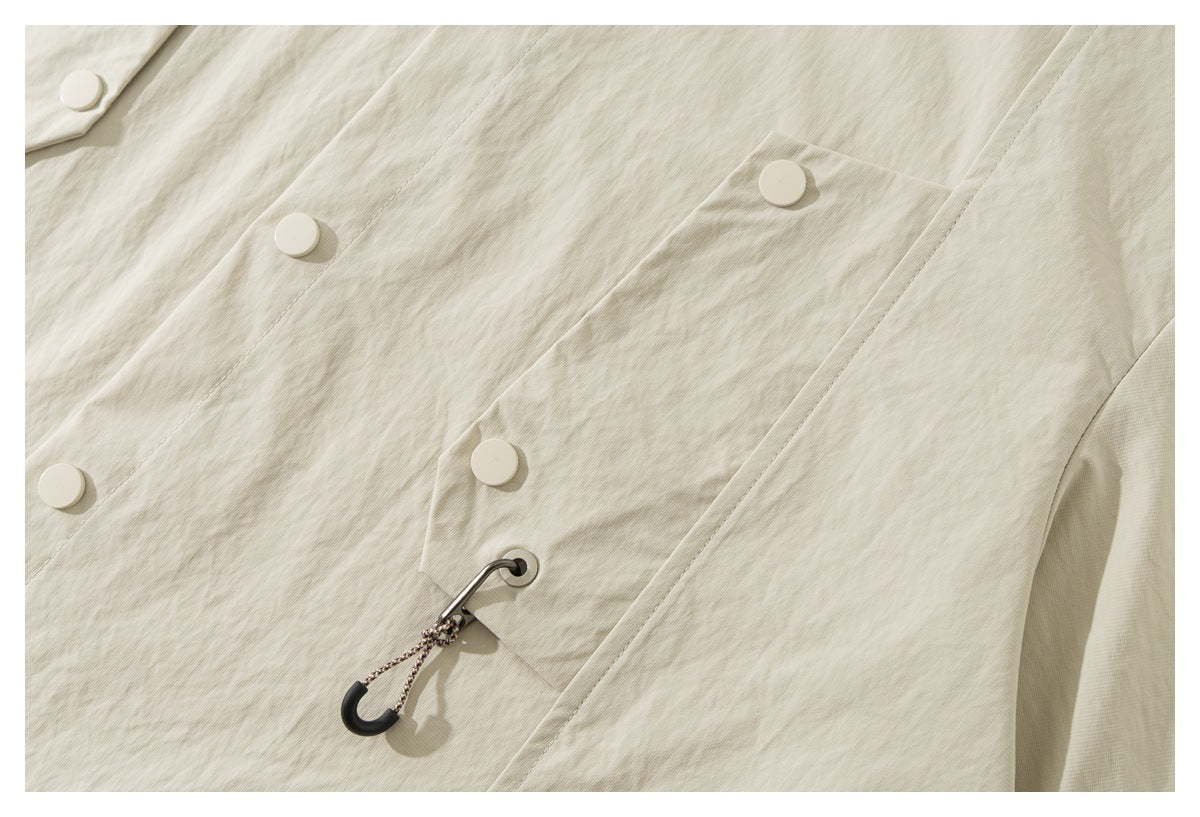 Close-up of an ivory shirt-jacket front with large snaps, a flap pocket, and a cord loop detail.