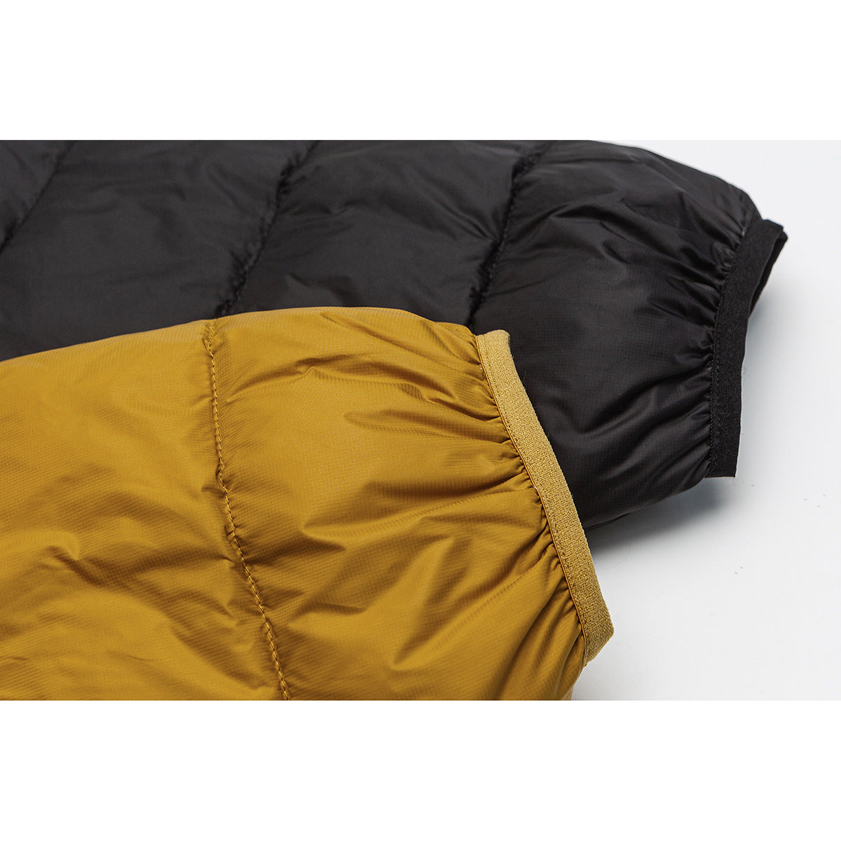 Close-up of mustard and black quilted jacket sleeves showing contrasting cuff edges.