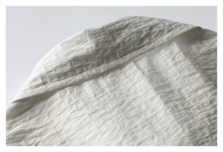 Close-up of pale ivory textured fabric with a broad folded edge.