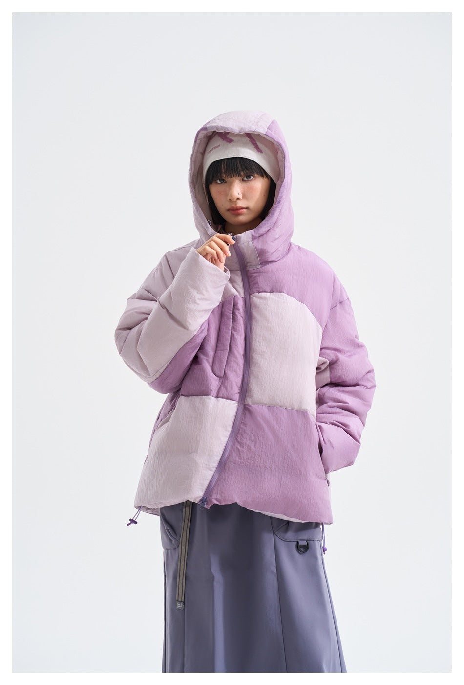 Model wearing the purple color-block puffer jacket with hood up and hem drawcords, front view
