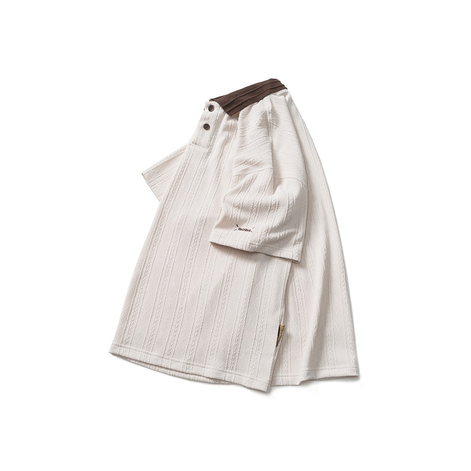 Cream short-sleeve polo shown flat, with a dark brown collar, buttons, and a raised geometric knit pattern.