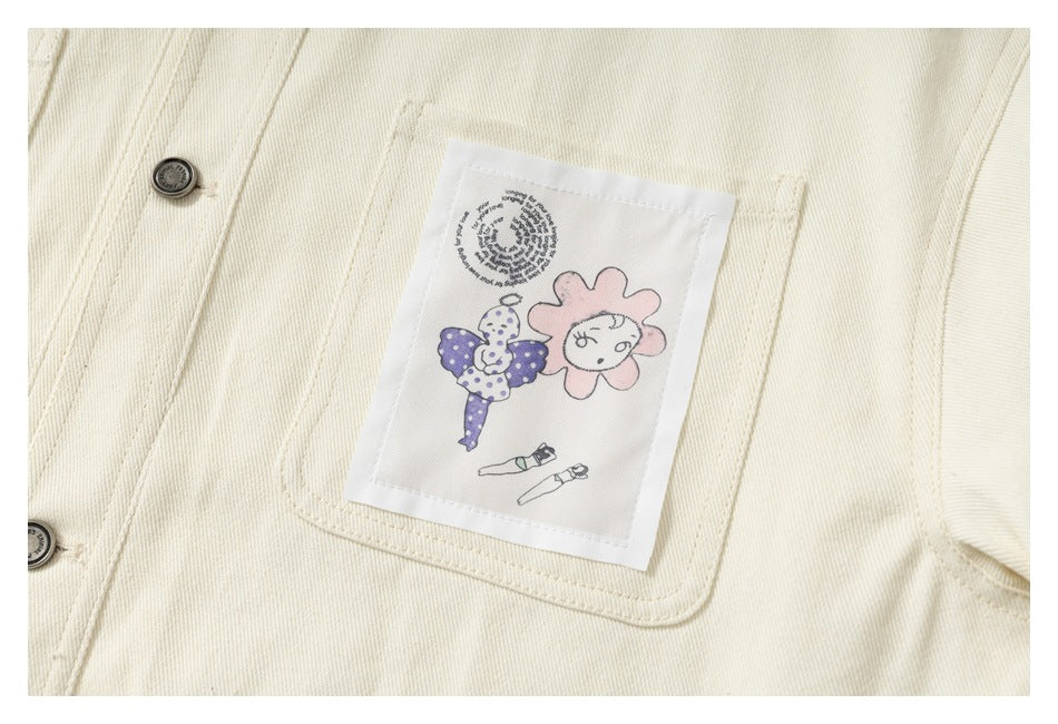 Close-up of an illustrated pink flower and figure patch on the ivory jacket chest pocket.