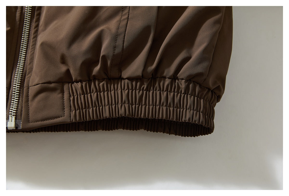 Close-up of the brown jacket's gathered elastic hem and adjacent zipper.