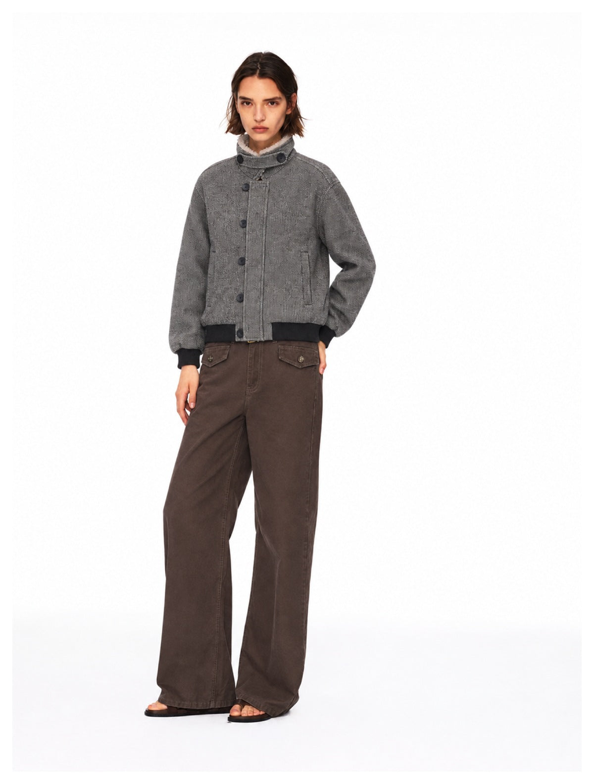 Front view of a gray button-front jacket with black ribbed trim, styled with wide-leg brown pants.