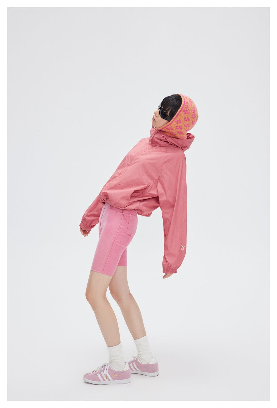 Model wearing a dusty pink hooded jacket and pink cycling shorts, posed against a light background.