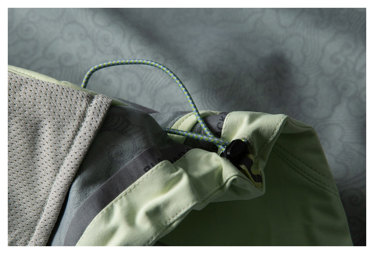 Close-up of pale green garment waistband with drawcord, toggle, and perforated lining.