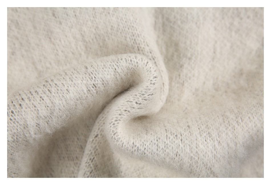 Extreme close-up of soft-looking cream knit fabric folded to show its open stitch texture.