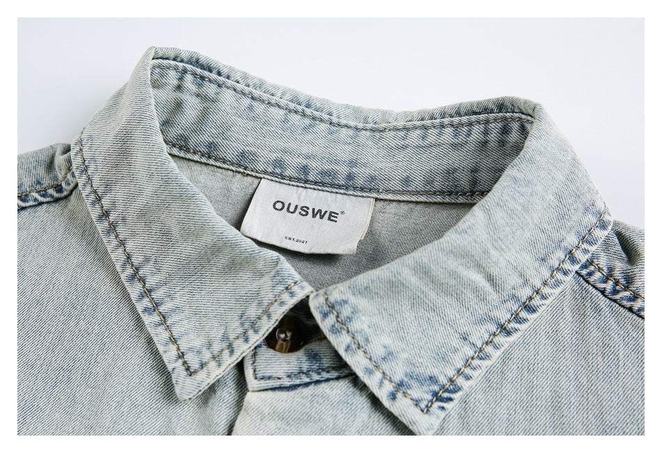 Close-up of the washed-blue shirt's pointed collar, button, stitching, and sewn-in neck label.