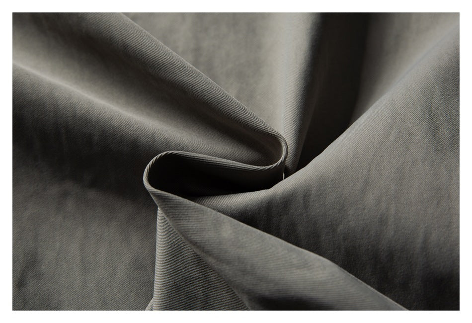 Close-up of dark gray woven fabric draped into soft folds, showing a fine diagonal texture.