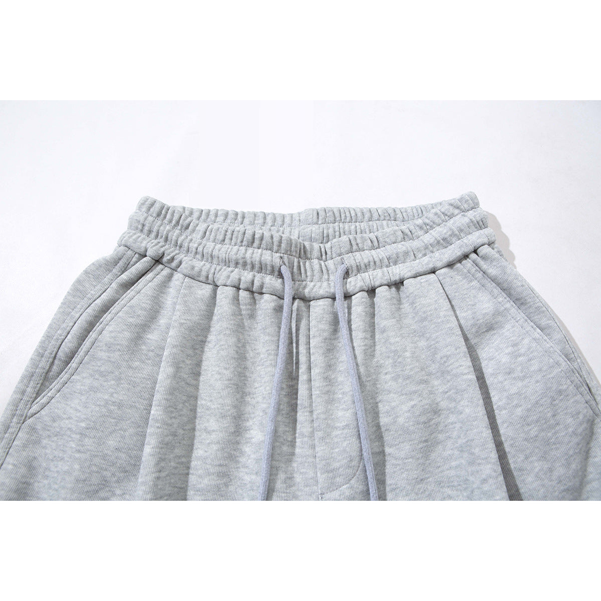 Close-up of light gray wide-leg sweatpants showing the gathered elastic waistband and long drawstring.