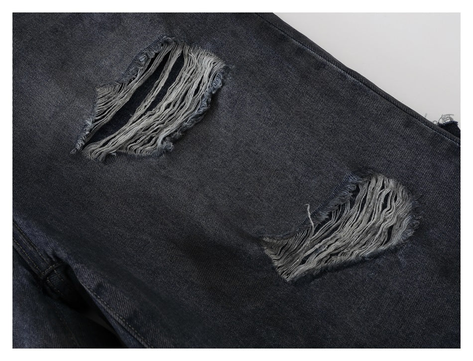 Close-up of two frayed distressed openings on dark gray jeans.