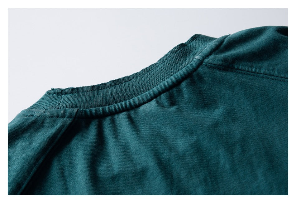 Close-up of the dark teal garment's ribbed neckline and shoulder seams.