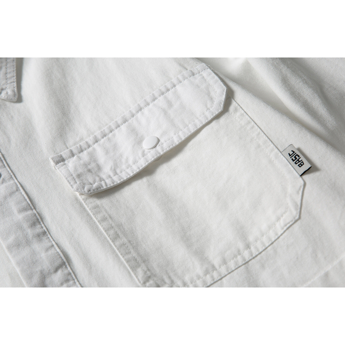 Close-up of a white shirt pocket with a buttoned flap and small woven side tag.