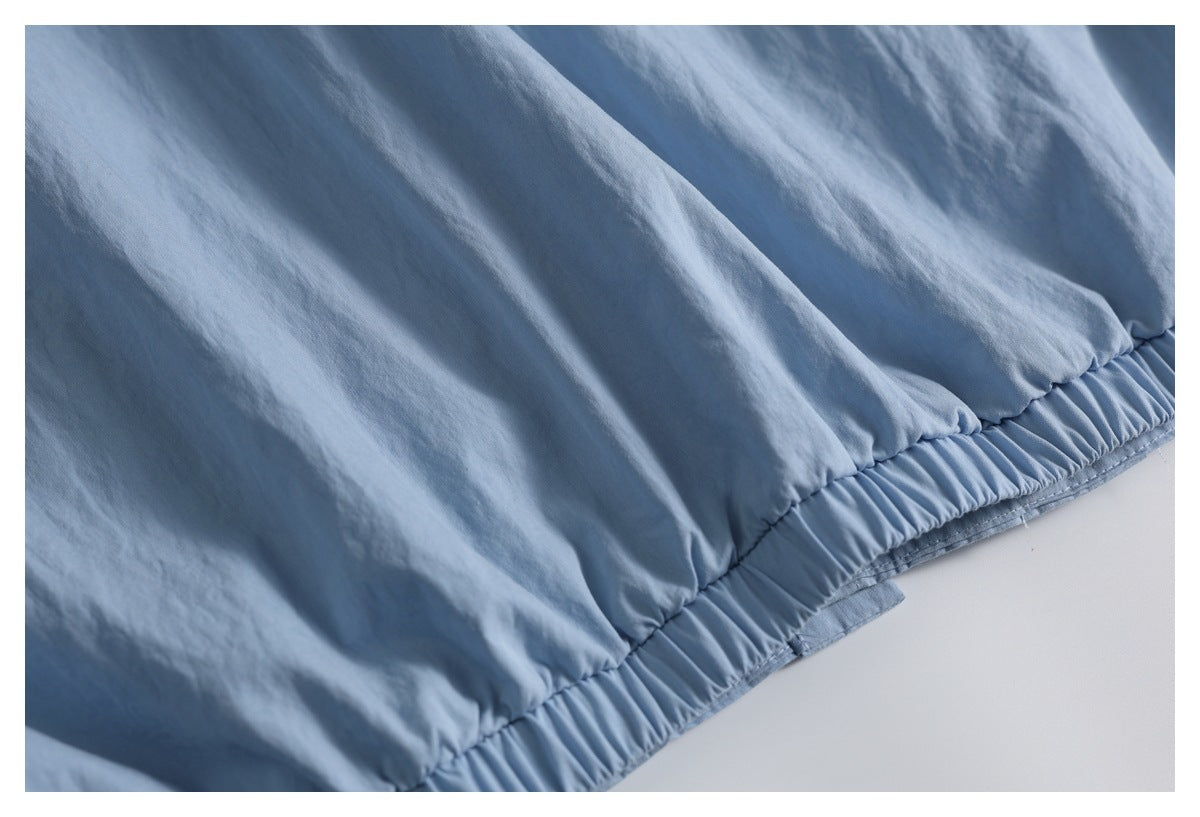 Close-up of a gathered elasticized edge on the light blue garment.