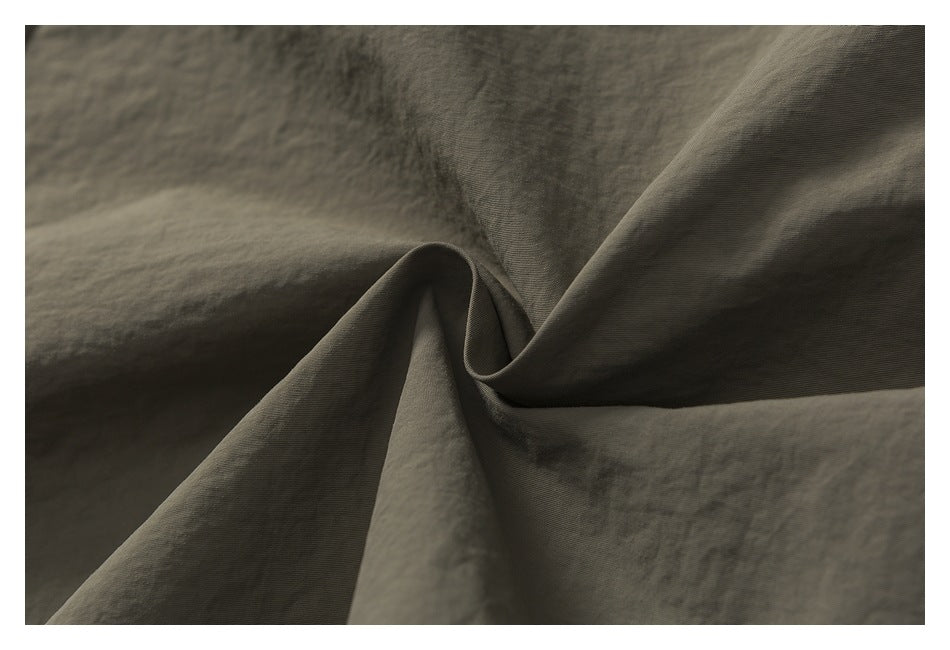 Close-up of olive-khaki garment fabric gathered into a soft fold.