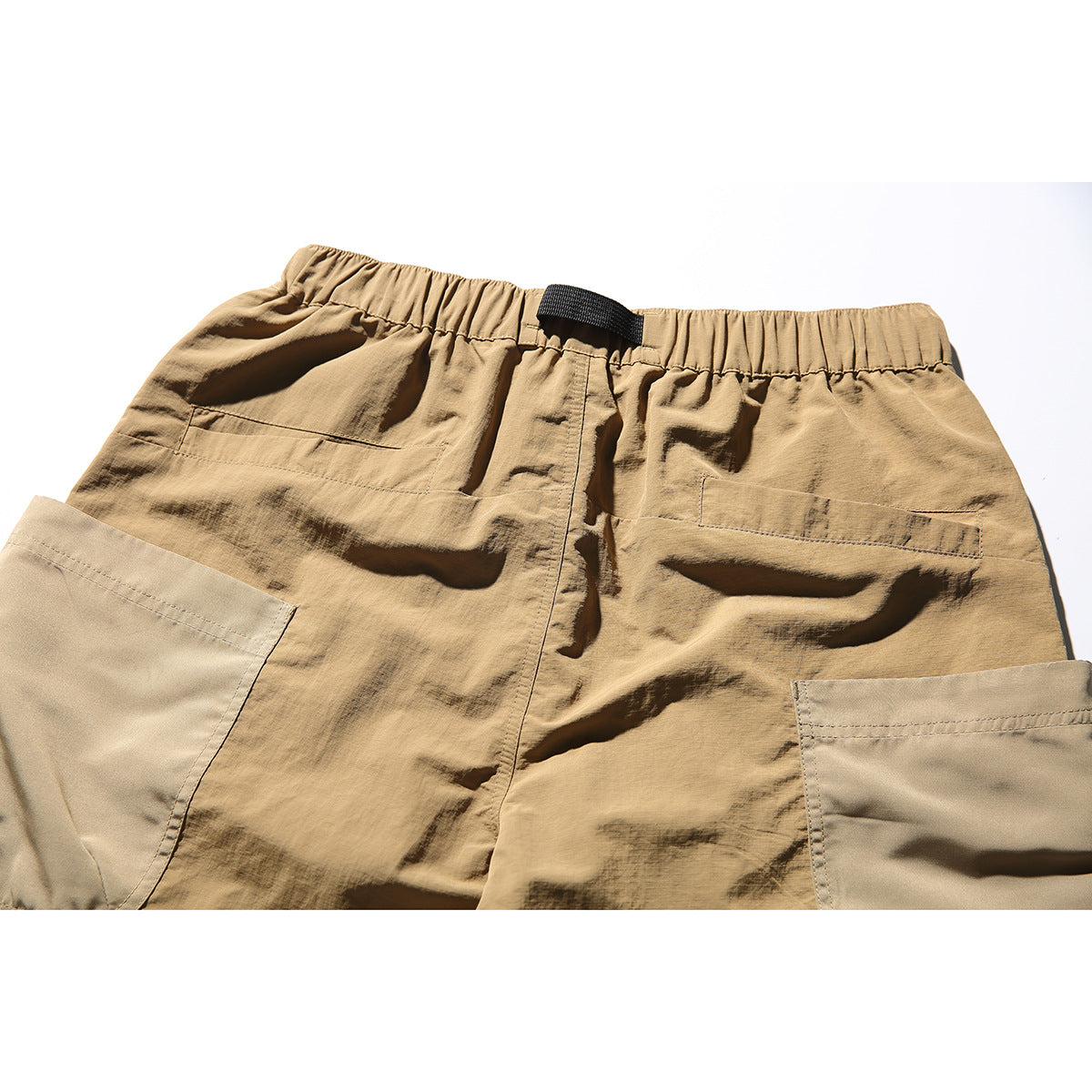 Close-up of the back of tan shorts with an elastic waist, black belt loop, and large patch pockets.