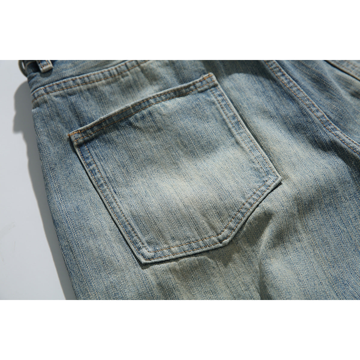 Close-up of a faded blue denim back pocket with contrast stitching.