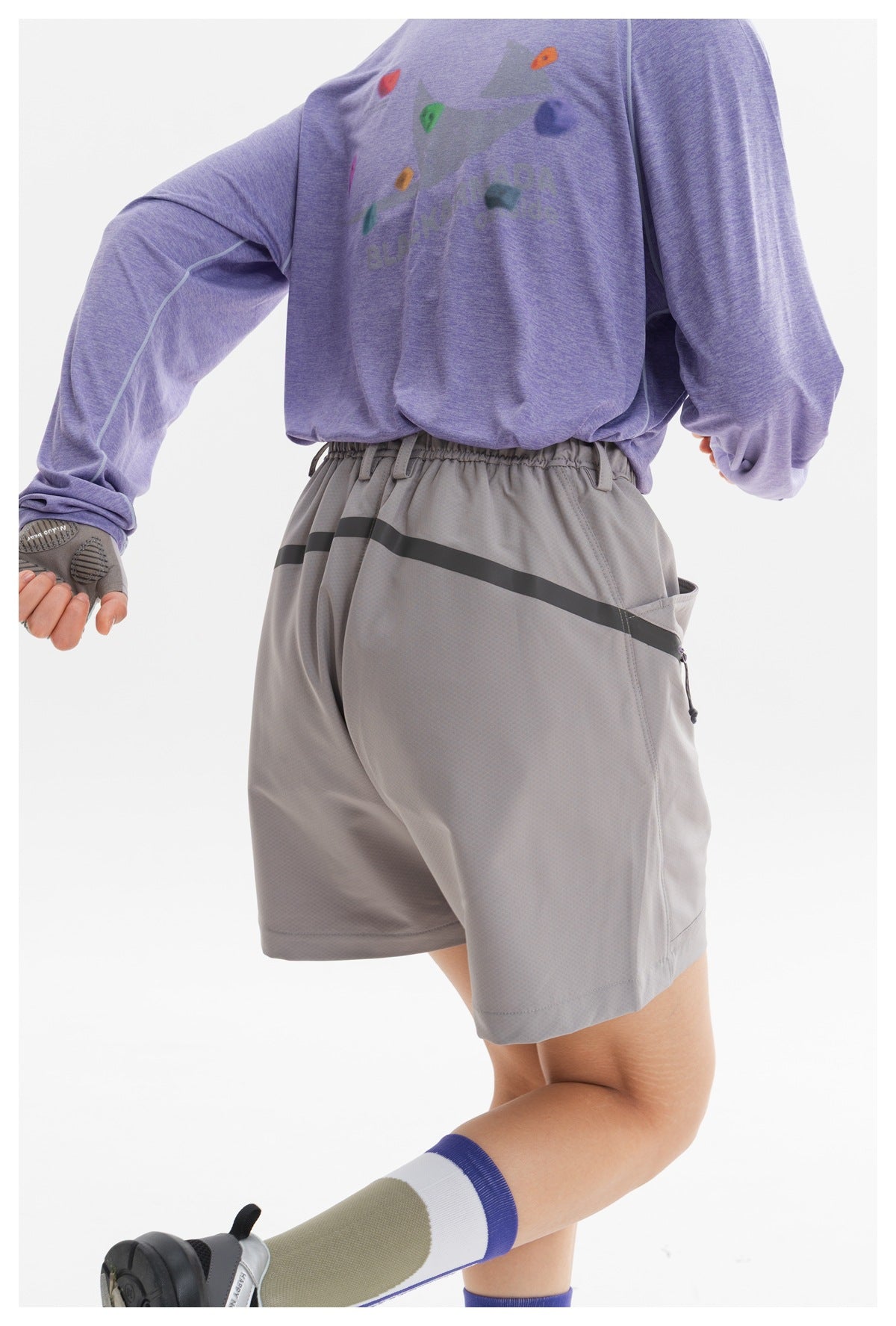 Close-up of gray shorts with an elastic waistband and dark stripe, paired with a lavender top bearing a colorful graphic.