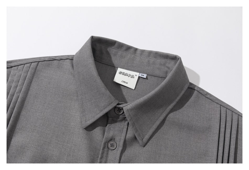 Close-up of a gray shirt collar, top buttons, shoulder pleats, and a sewn SAPA size label.