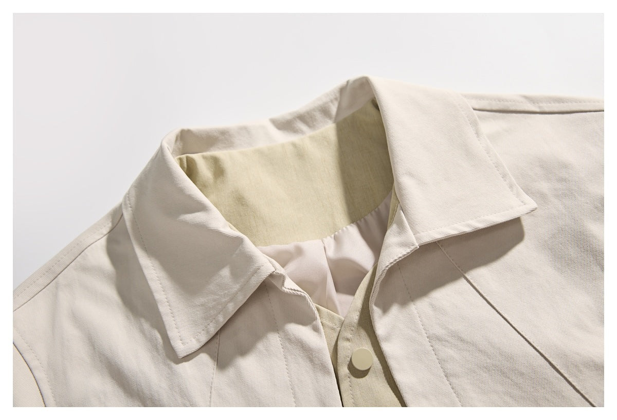 Close-up of a cream jacket's pointed collar, inner lining, front seam and snap fastener.