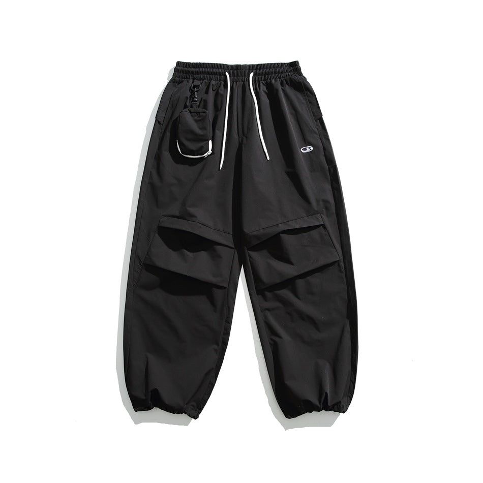 Black wide-leg pants with white drawstring, clipped pouch, pleated knee panels and gathered ankle cuffs, flat lay