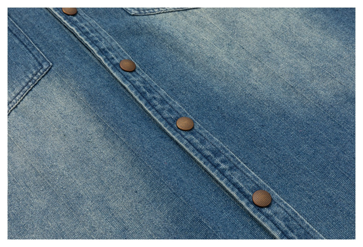 Close-up of a blue denim snap-button placket with copper-colored buttons and visible stitching.