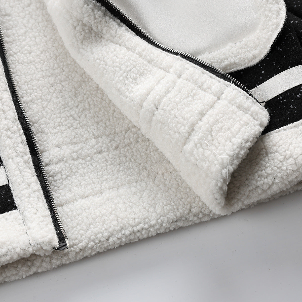 Close-up of the coat's cream fleece lining, front zipper and pale trim against black flecked outer fabric.