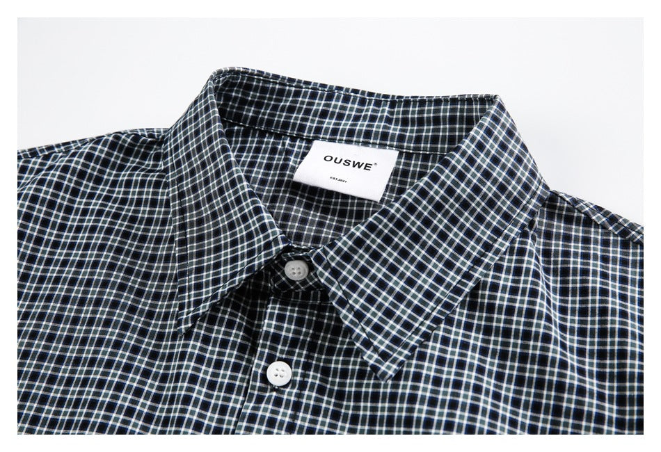 Close-up of a black checked shirt collar, white buttons, and a sewn-in OUSWE label.