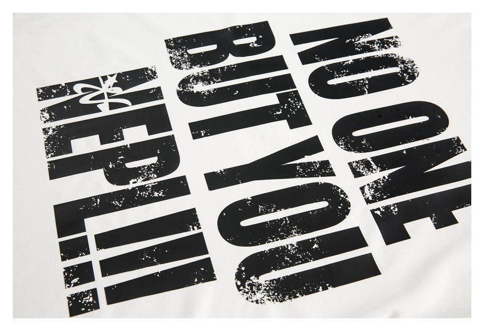 Close-up of oversized distressed black lettering printed on white T-shirt fabric.
