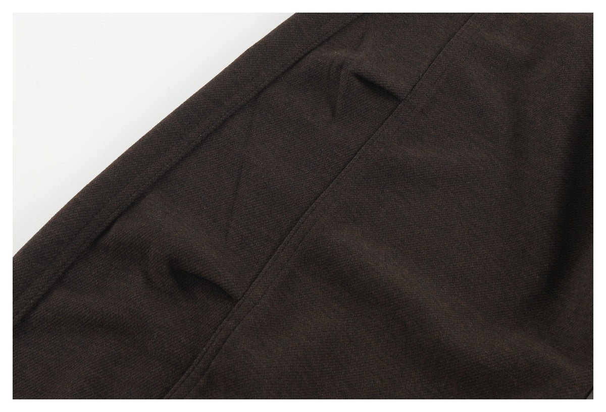 Close-up of dark brown pants fabric with a seam and pocket opening.