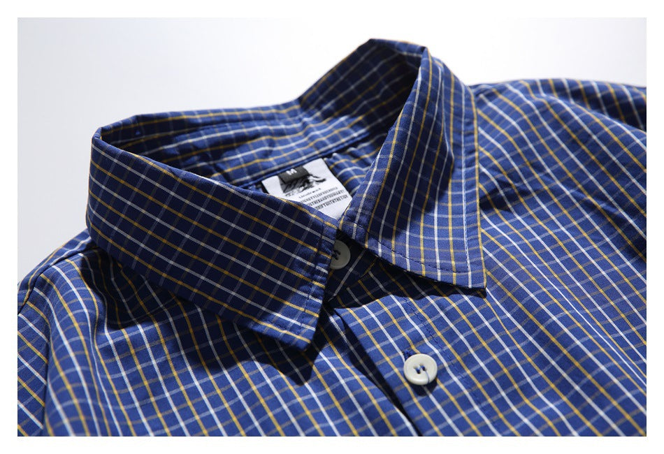 Close-up of a blue plaid button-up shirt collar with white buttons and a sewn neck label.