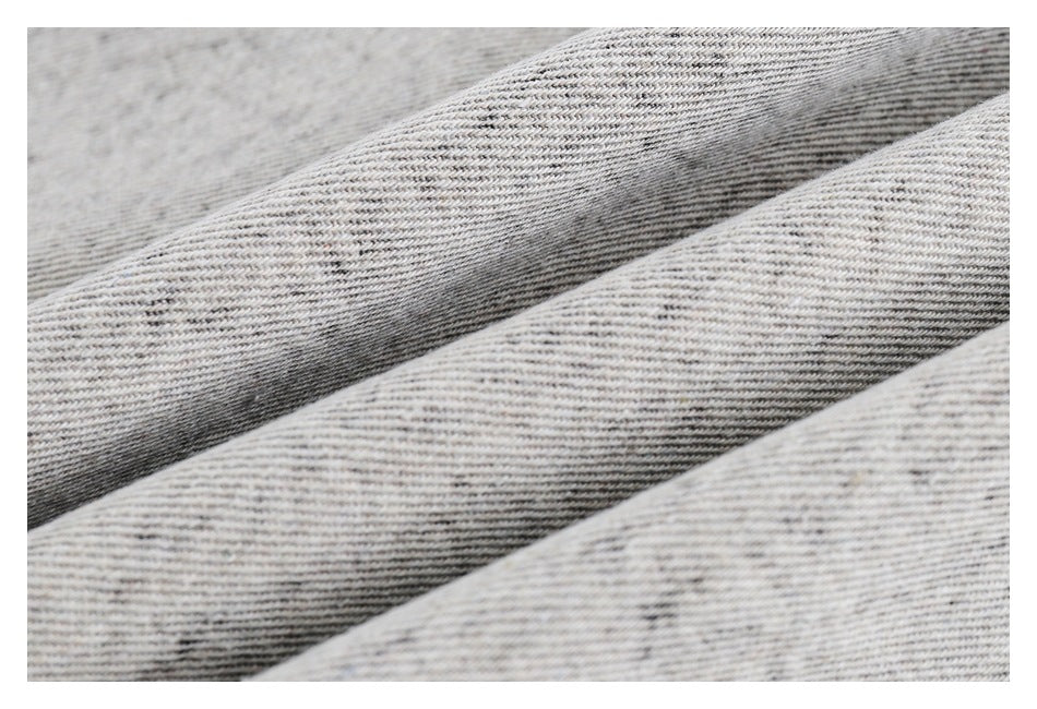 Close-up of light gray, subtly heathered fabric with fine diagonal texture and soft folds.