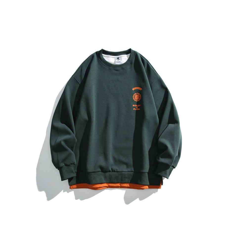 Dark green crewneck sweatshirt flat lay with orange chest crest print and orange layered underhem