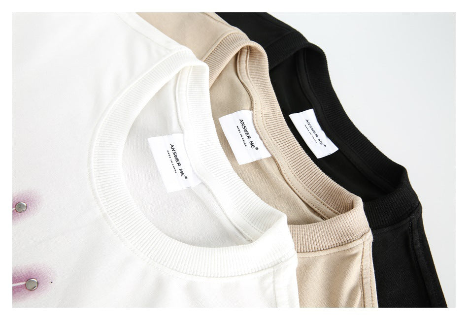Close-up of white, beige, and black crewneck tops showing ribbed collars and sewn neck labels.