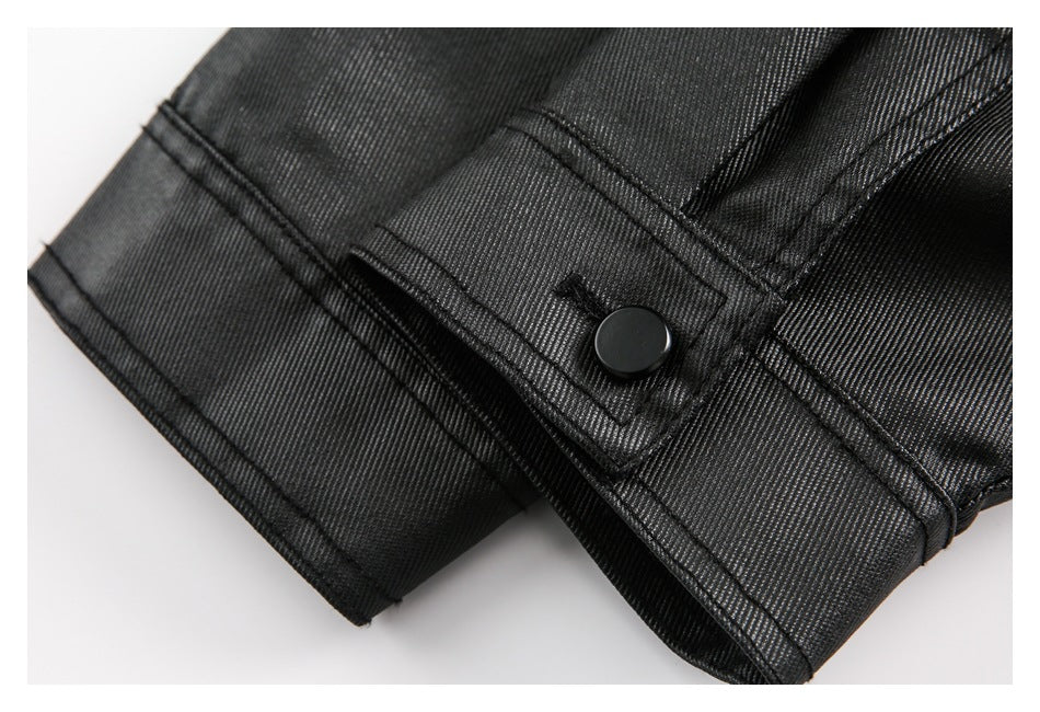 Close-up of a black garment's stitched tab with a round black button and overlapping seams.