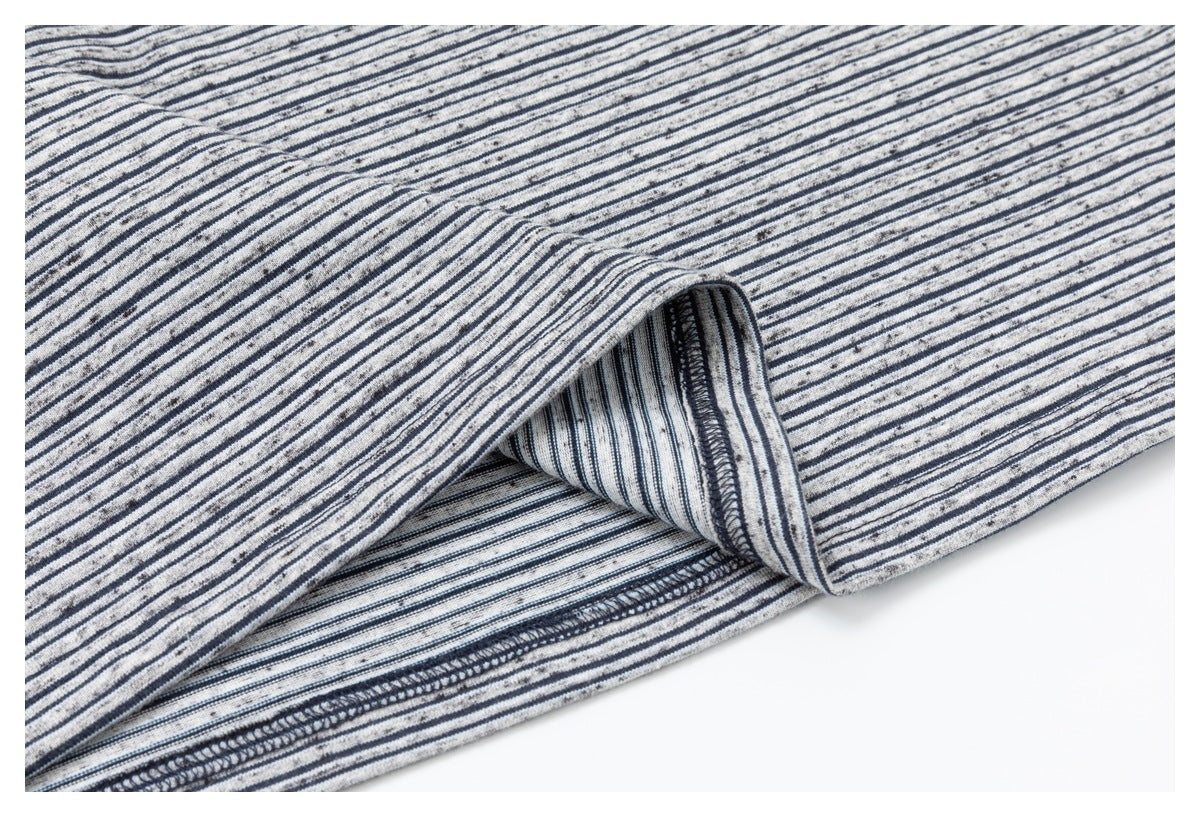 Close-up of the striped garment's folded hem, showing the inner fabric and dark overlock stitching.