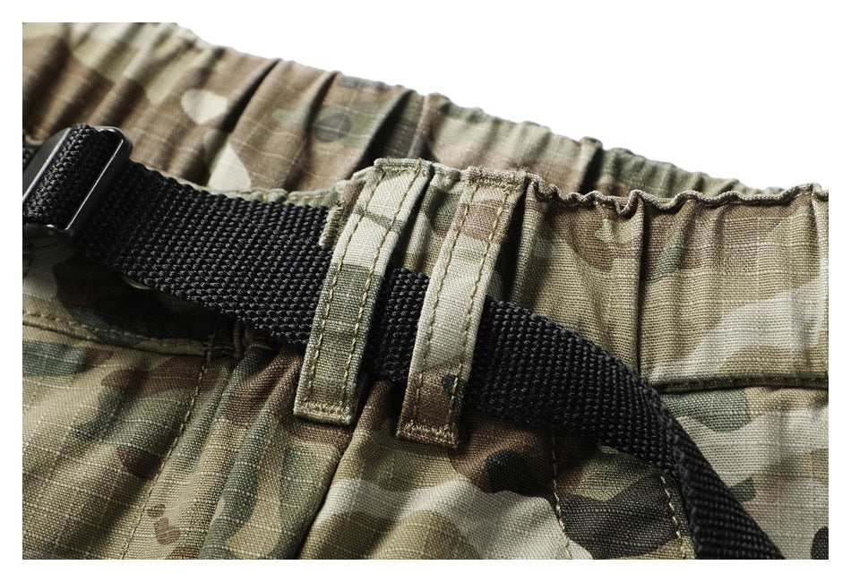 Close-up of a black woven belt threaded through loops on camouflage pants with an elastic waistband.