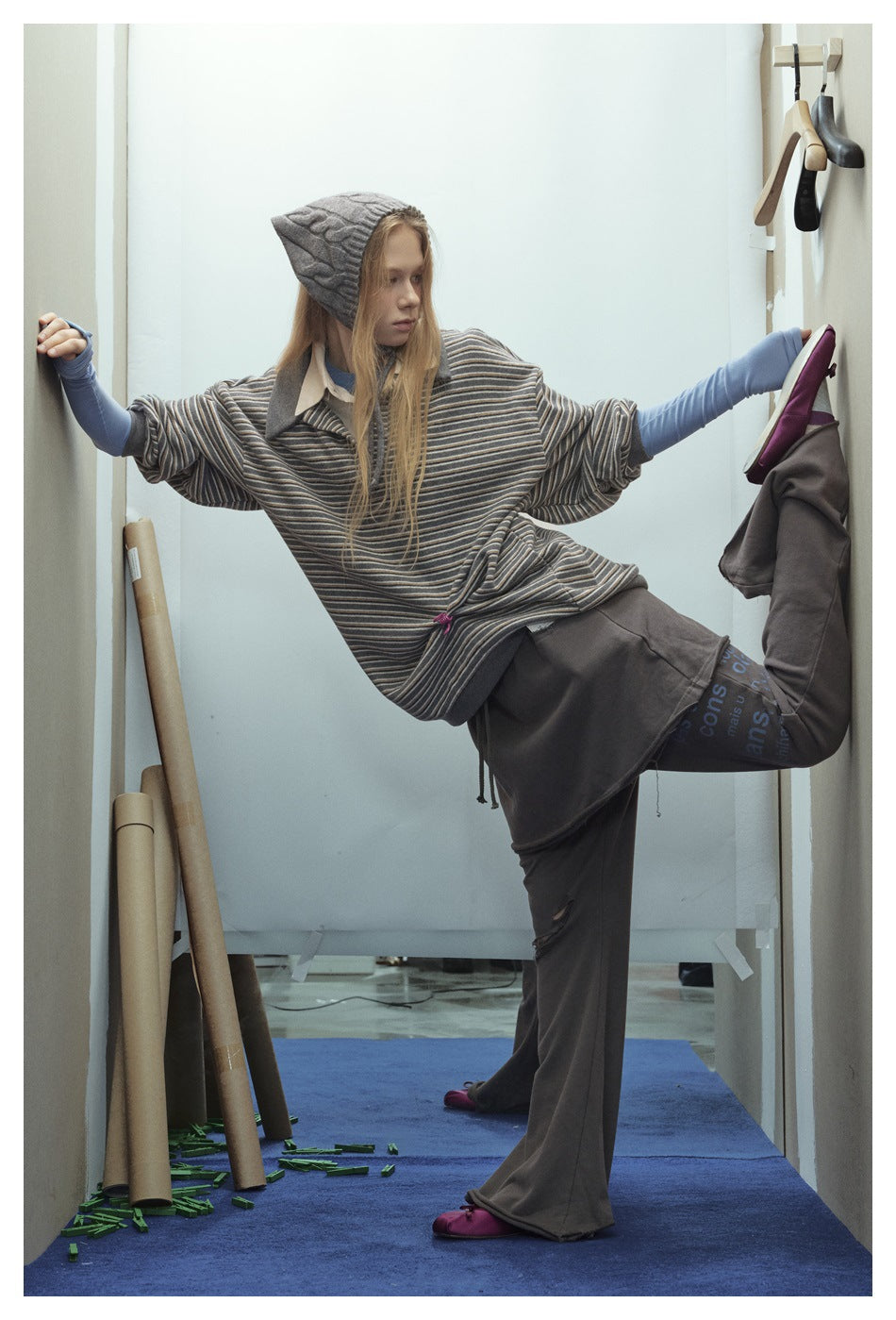 Model wearing a loose gray striped pullover with short sleeves and contrast collar, posed with arms outstretched.