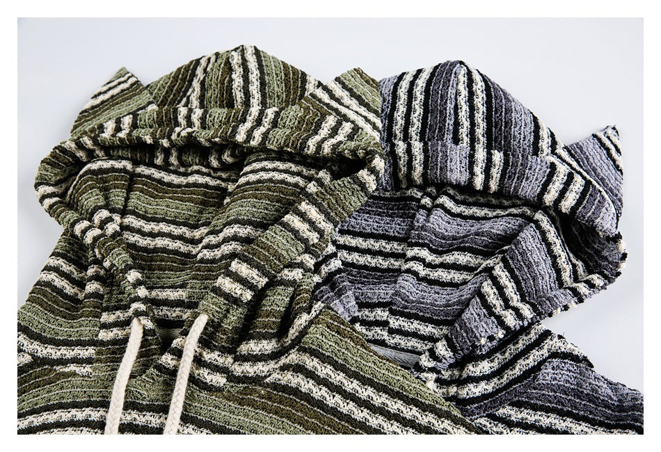 Close-up of two striped hooded pullovers, one olive green and cream and the other gray, black, and cream.