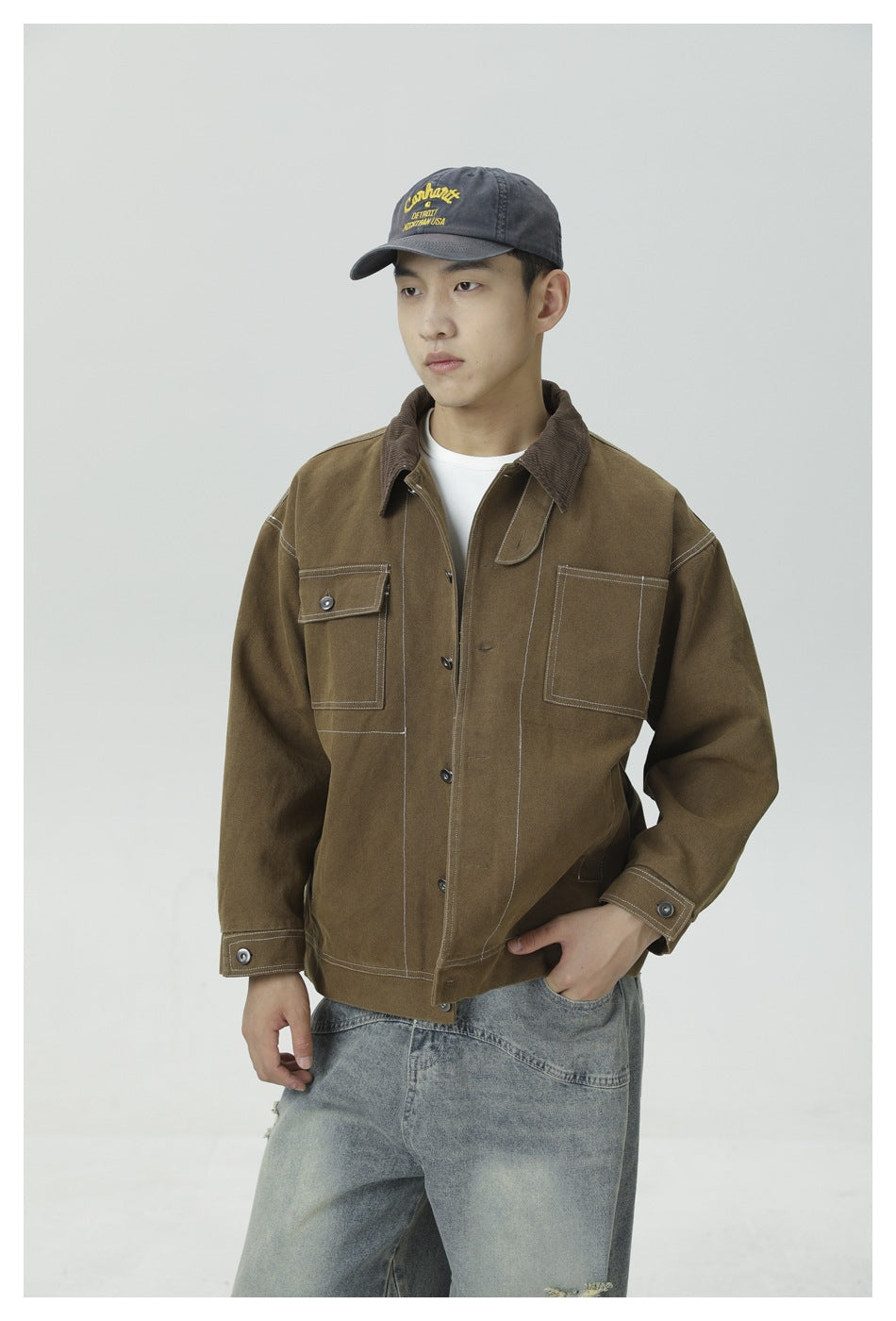 Front view of a model wearing a brown work jacket with a corduroy collar, button cuffs, and two chest pockets.