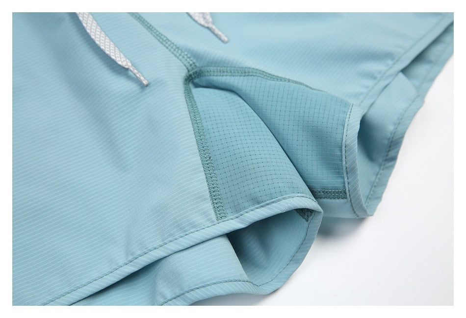 Close-up of aqua shorts showing the inner leg panel, seams, and stitching.