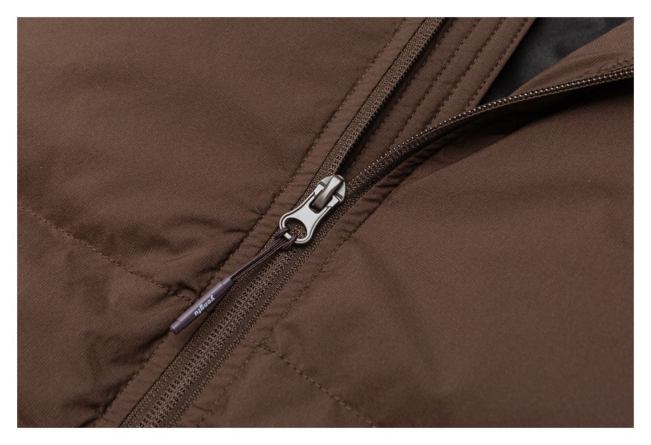 Close-up of a brown garment's zipper, pull tab, and stitched fabric panels.