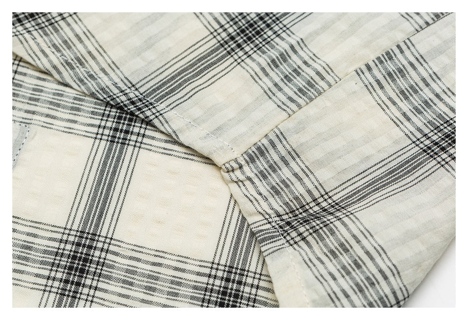 Close-up of a stitched seam on cream-and-black plaid fabric.