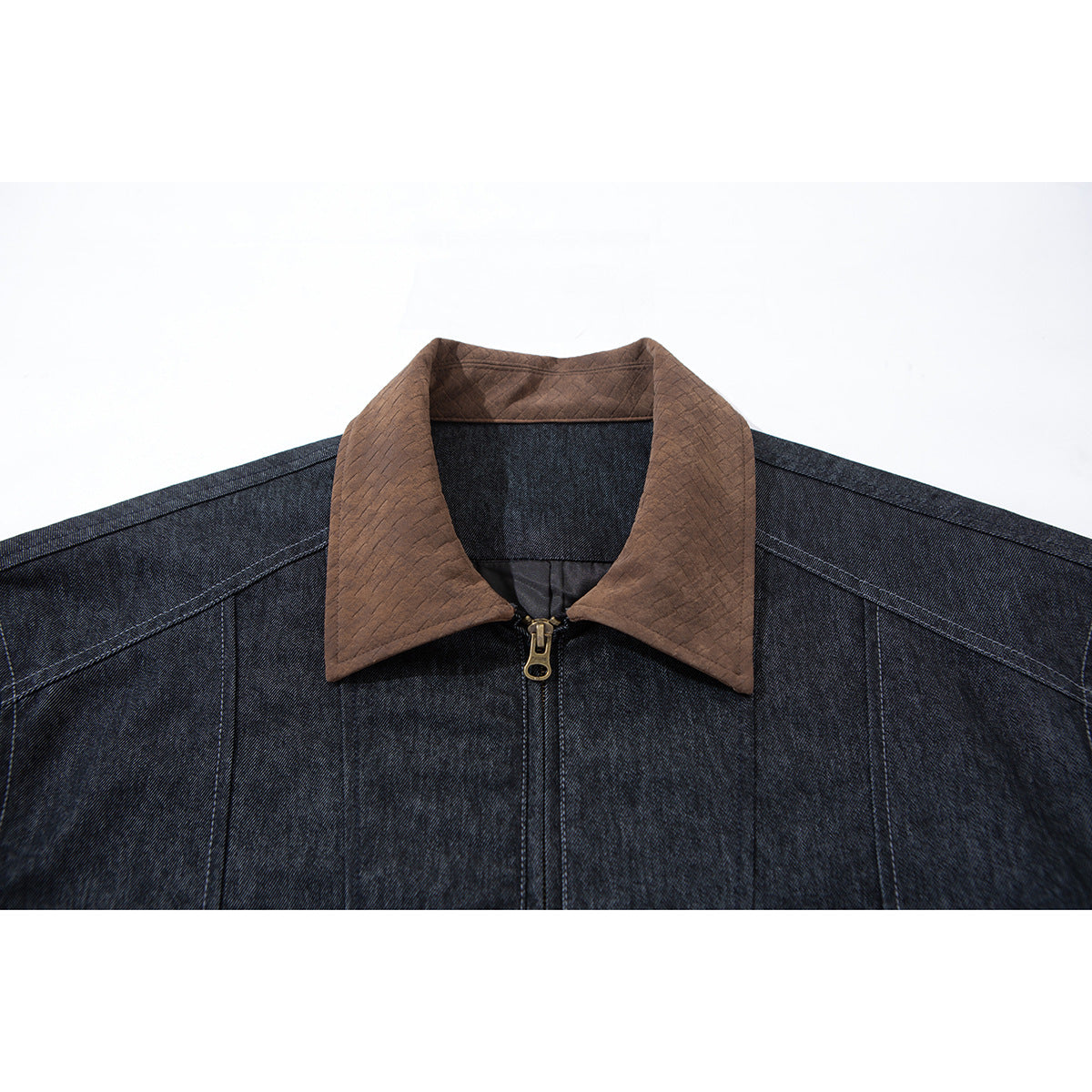 Close-up of a dark indigo jacket's front, showing its brown quilted collar and brass-colored zipper pull.